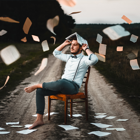 man on chair with flying pages and books