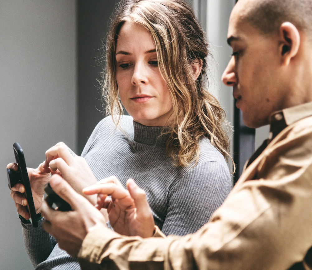 man och kvinna som visar något på sina mobiltelefoner